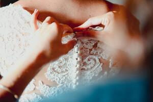 Fotografie de artă Close-up of a bridesmaid buttoning up, corinafotografia, (40 x 26.7 cm)
