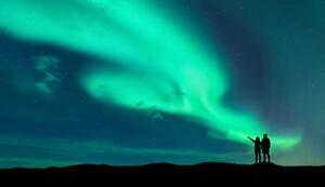 Fotografie Aurora borealis and silhouette of man and woman, den-belitsky