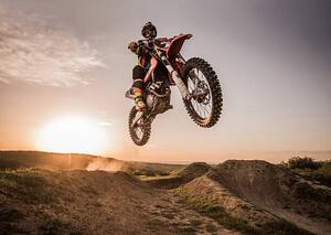 Fotografie Motocross rider performing high jump at sunset., skynesher