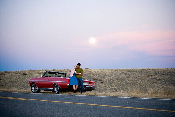 Fotografie de artă man and woman next to a red convertible, Mike Kemp, (40 x 26.7 cm)