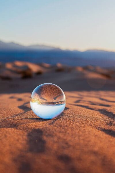Fotografie de artă Glass Sphere on Desert Sand, Lena Wagner, (26.7 x 40 cm)